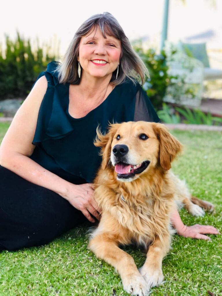 Woman smiling with her dog on grass.