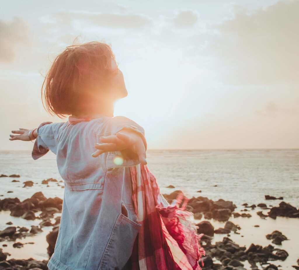 Person enjoying sunset by the rocky shore.